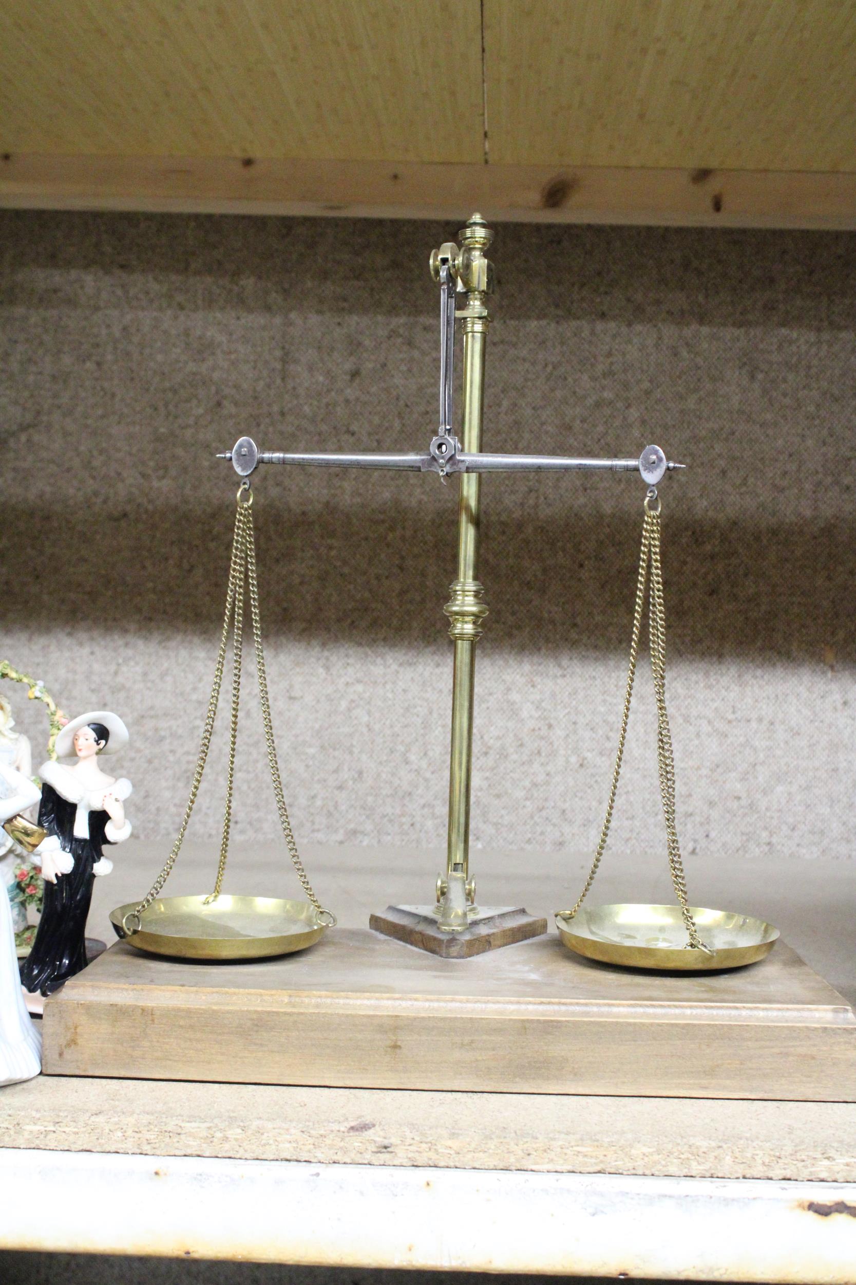 A SET OF BRASS BALANCE SCALES ON A WOODEN BASE