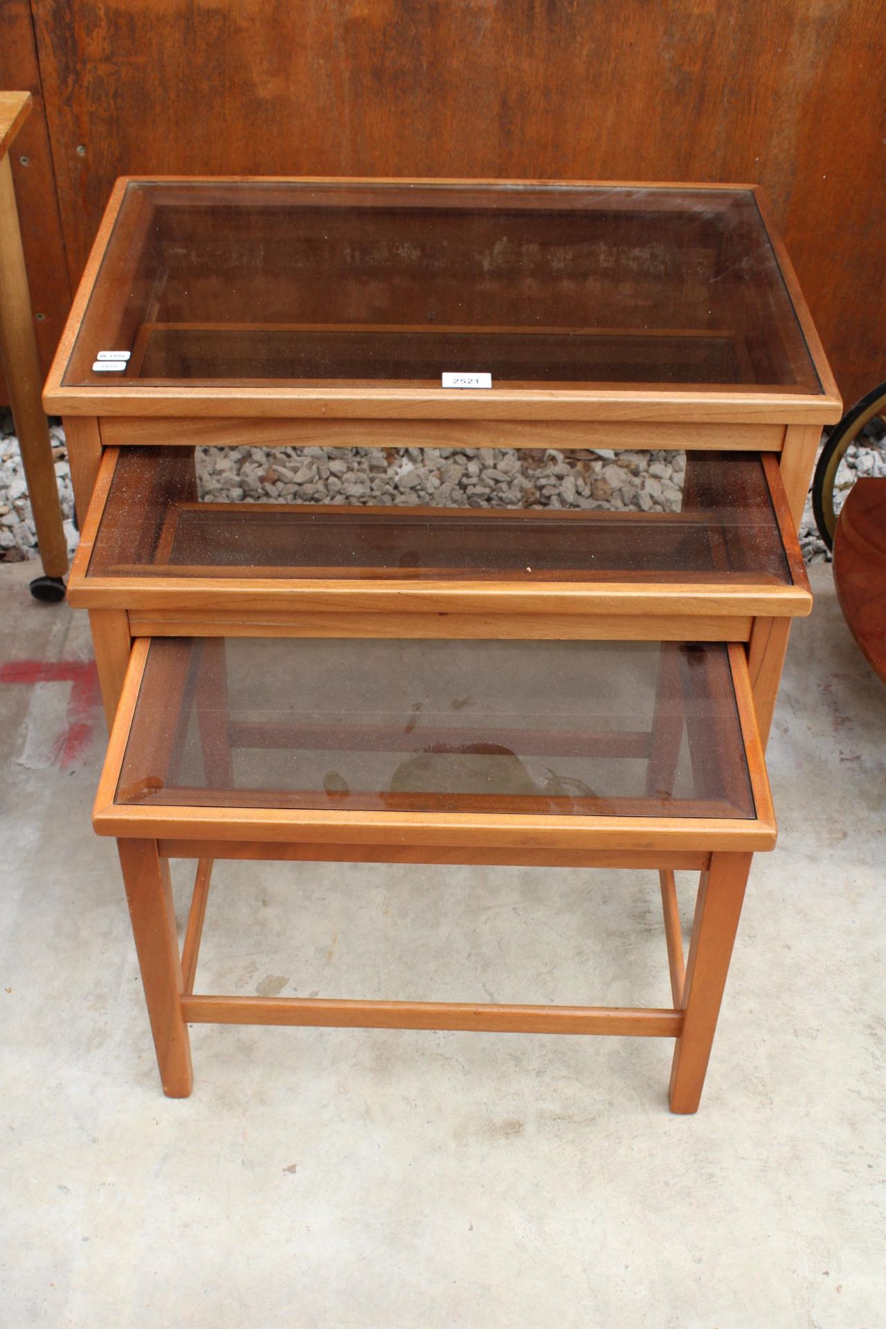 A RETRO TEAK NEST OF THREE TABLES WITH INSET GLASS TOPS