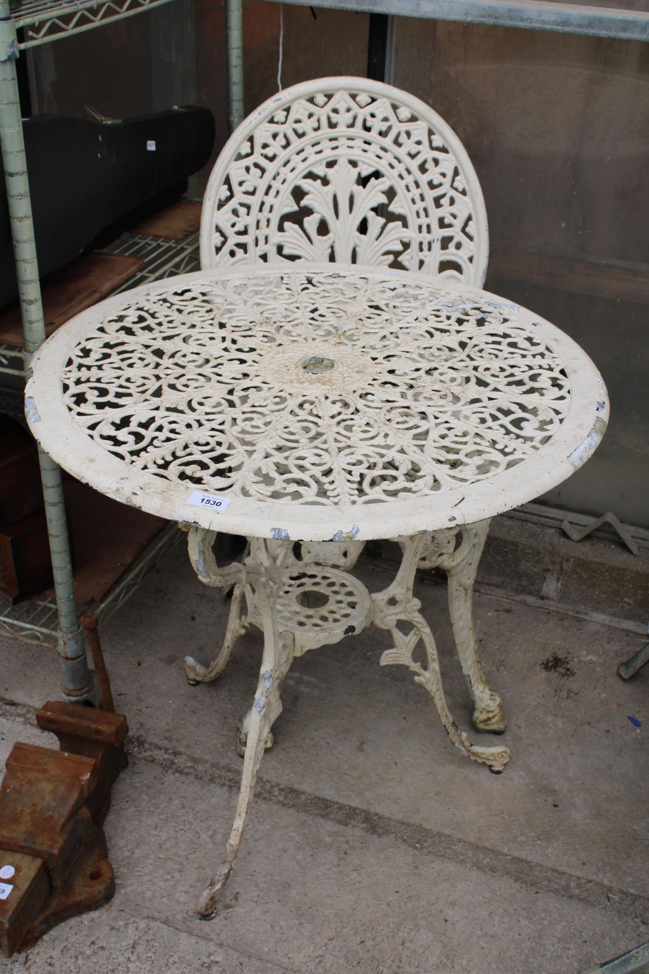 A CAST ALLOY BISTRO SET COMPRISING OF A ROUND TABLE AND ONE CHAIR