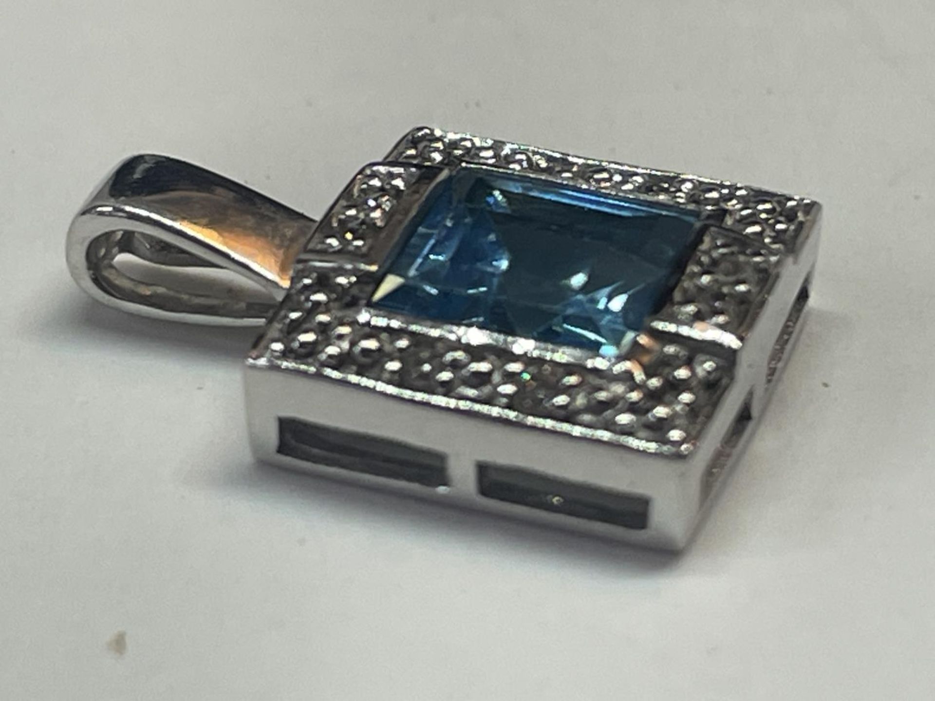 A 9 CARAT WHITE GOLD SQUARE PENDANT WITH CENTRE BLUE TOPAZ SURROUNDED BY DIAMONDS IN A - Bild 3 aus 5