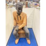 A LARG FIGURE OF A MAN SITTING IN A CHAIR