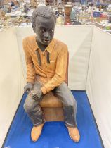 A LARG FIGURE OF A MAN SITTING IN A CHAIR