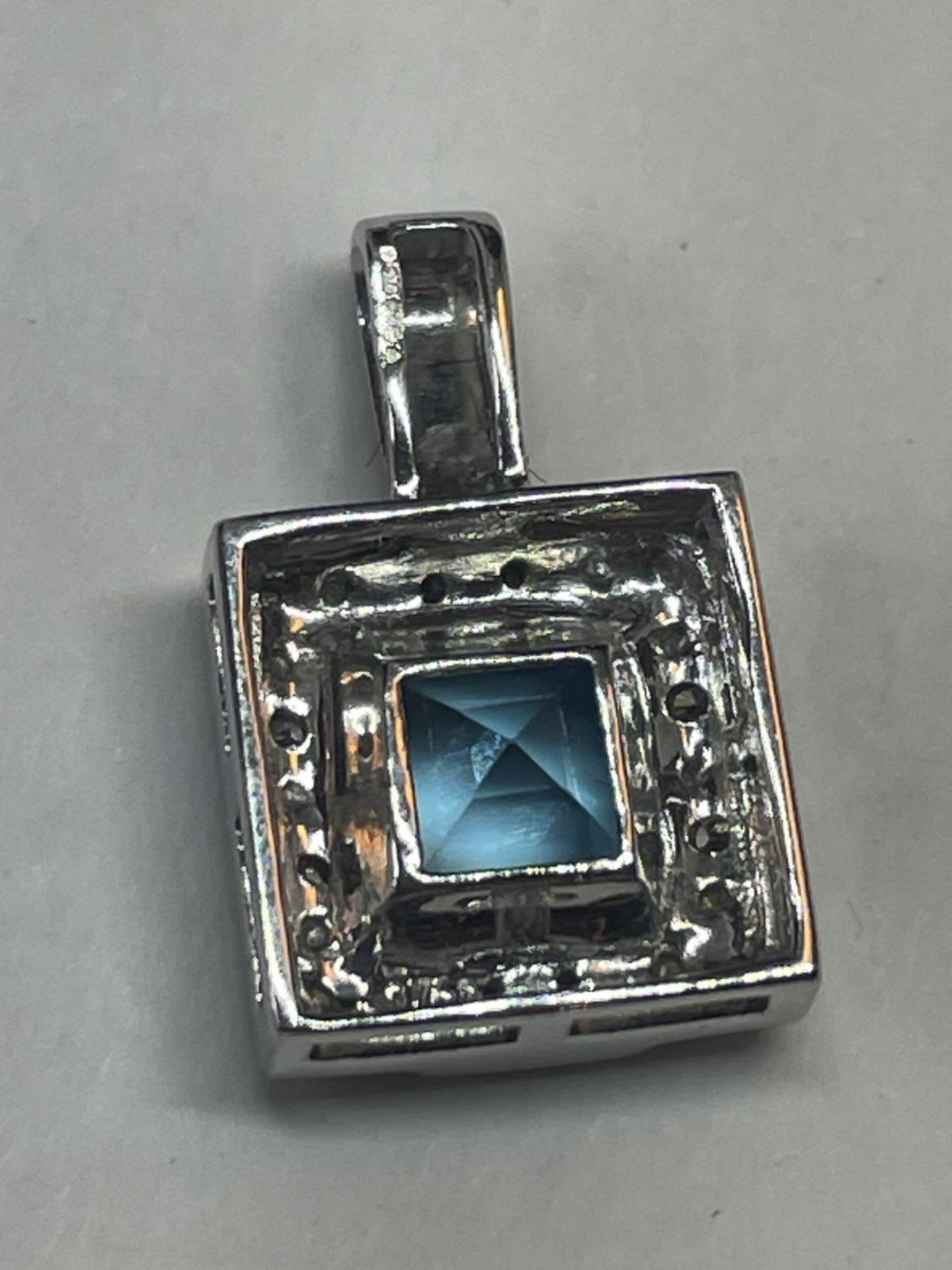 A 9 CARAT WHITE GOLD SQUARE PENDANT WITH CENTRE BLUE TOPAZ SURROUNDED BY DIAMONDS IN A - Image 4 of 5