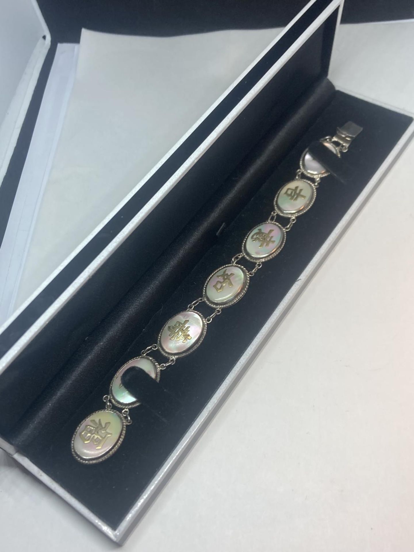 AN ORIENTAL SILVER AND MOTHER OF PEARL CHARACTER LINK BRACELET IN A PRESENTATION BOX