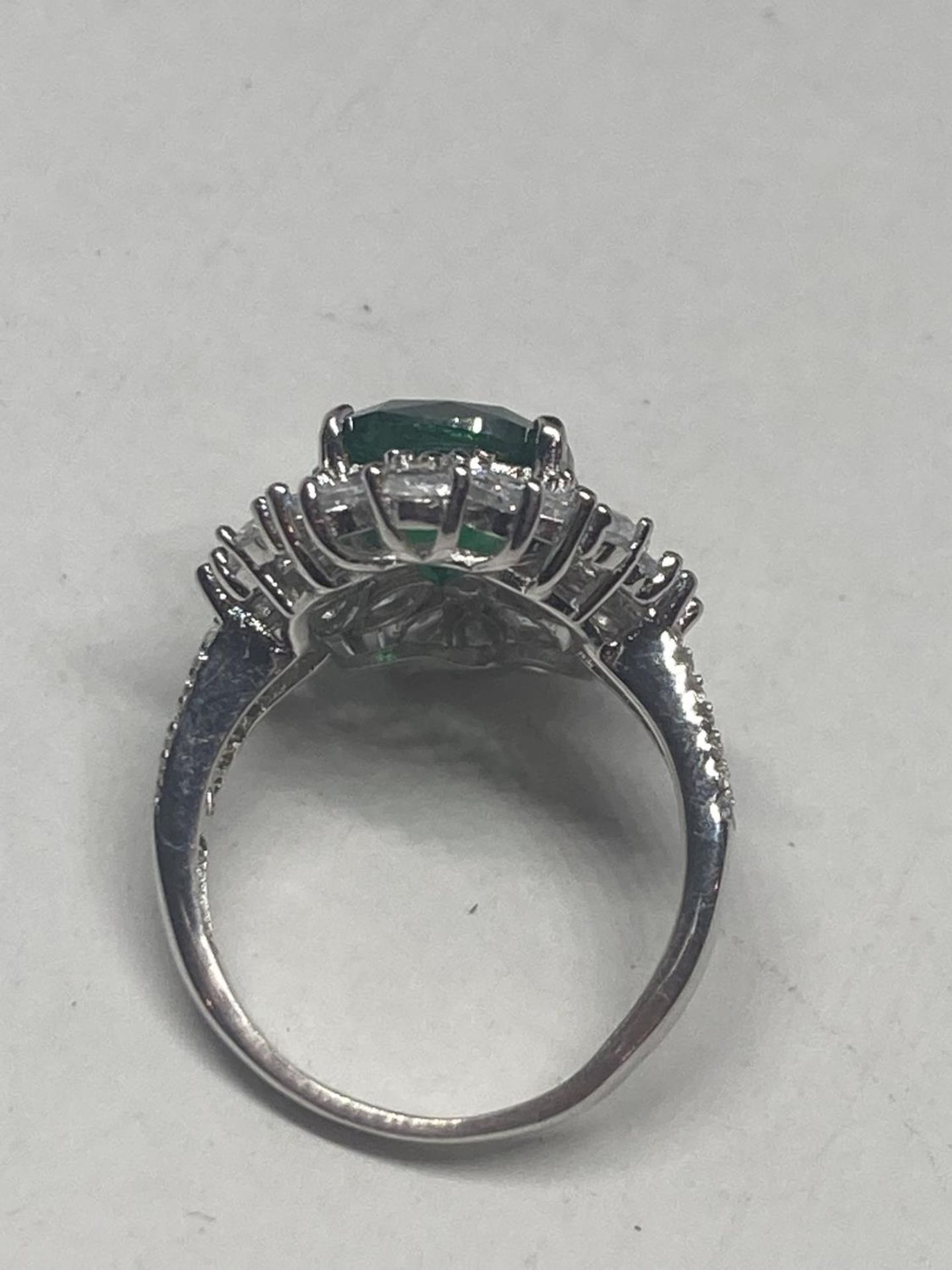 A WHITE METAL RING WITH A LARGE CENTRE LABORATORY GROWN EMERALD SURROUNDED BY CLEAR STONES SIZE S - Image 6 of 8