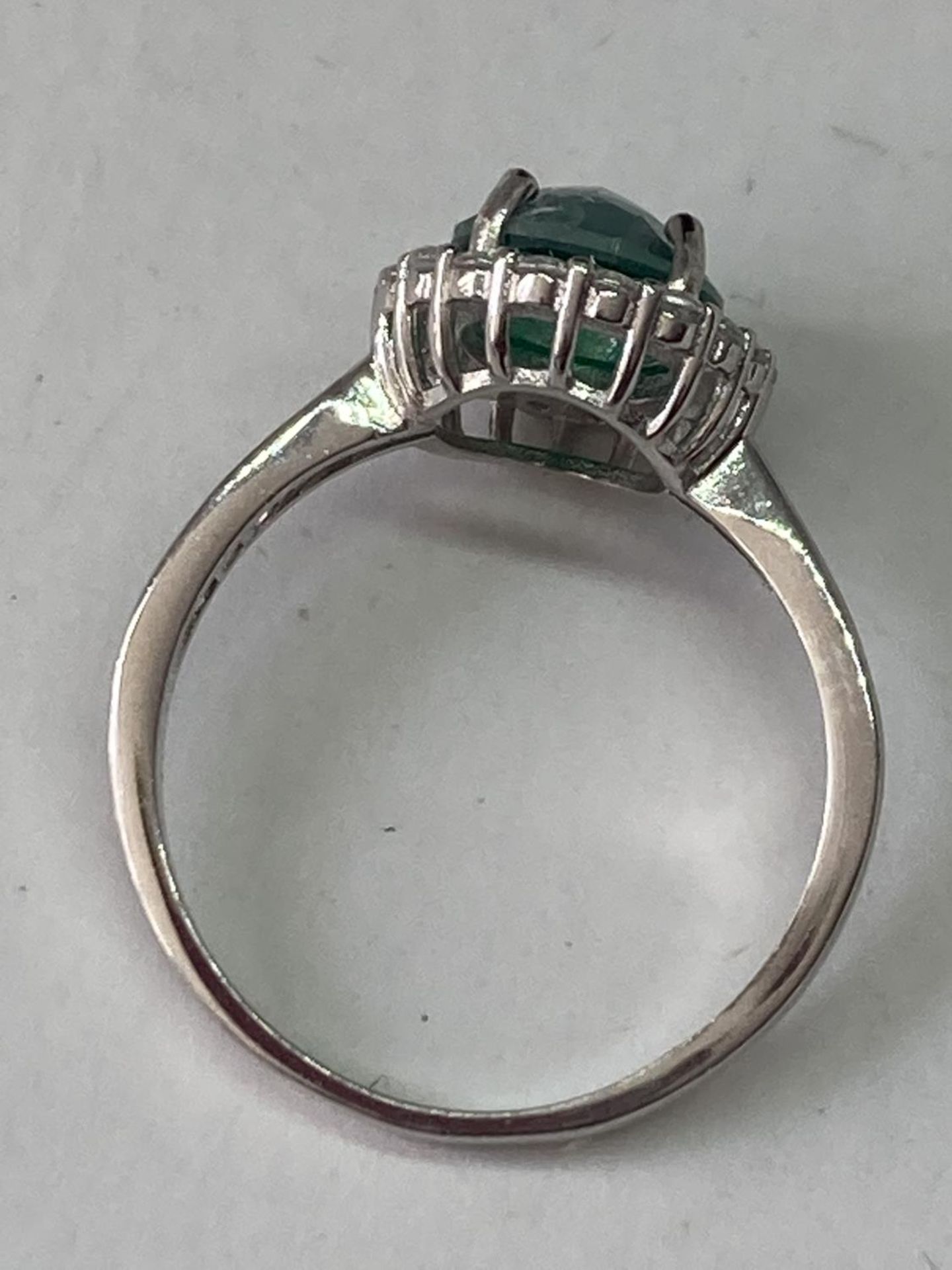 A WHITE METAL RING WITH A CENTRE LABORATORY GROWN EMERALD WITH CLEAR STONES SURROUNDING AND ON THE - Image 5 of 6