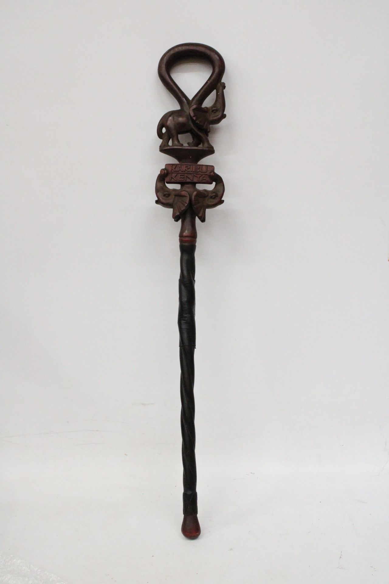 A HAND CARVED AFRICAN WALKING STICK, WITH ELEPHANT FIGURES TO THE TOP, WITH THE INSCRIPTION 'KARIBU,