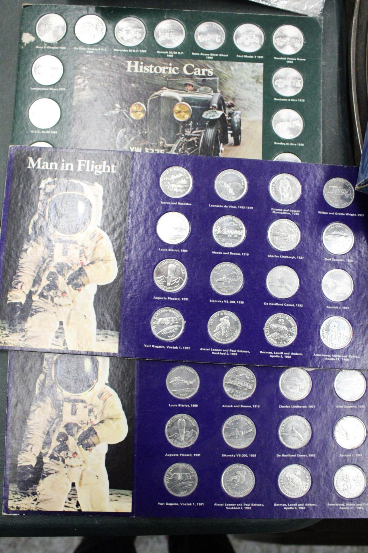 THREE SETS OF SHELL COLLECTABLE COINS ON CARDS, TO INCLUDE MAN'S FIRST FLIGHT X 2 AND HISTORIC CARS