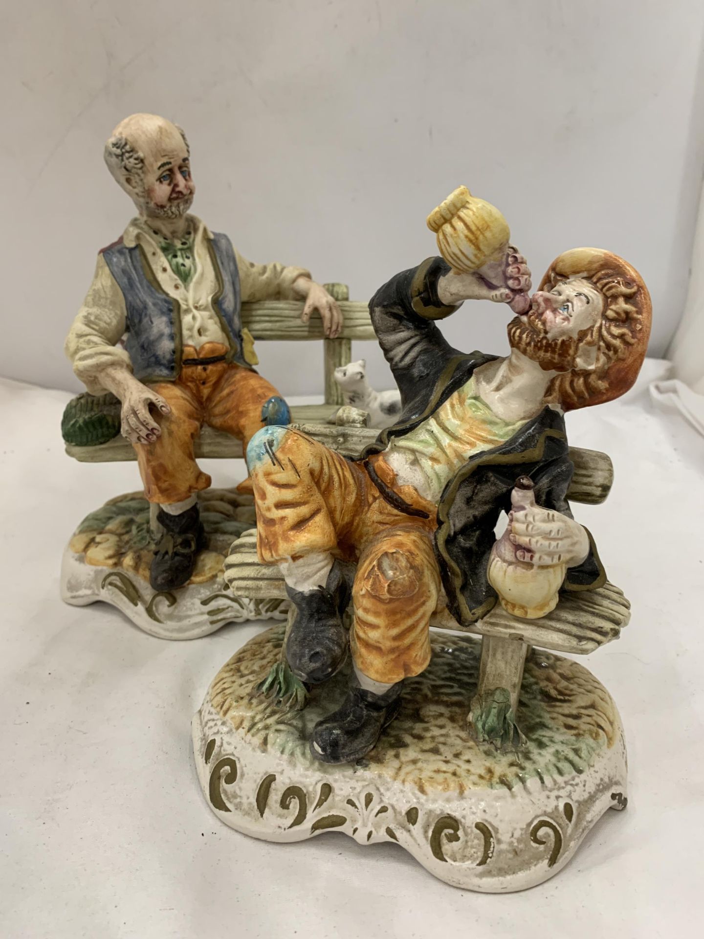 TWO CAPODIMONTE FIGURES OF MEN ON BENCHES