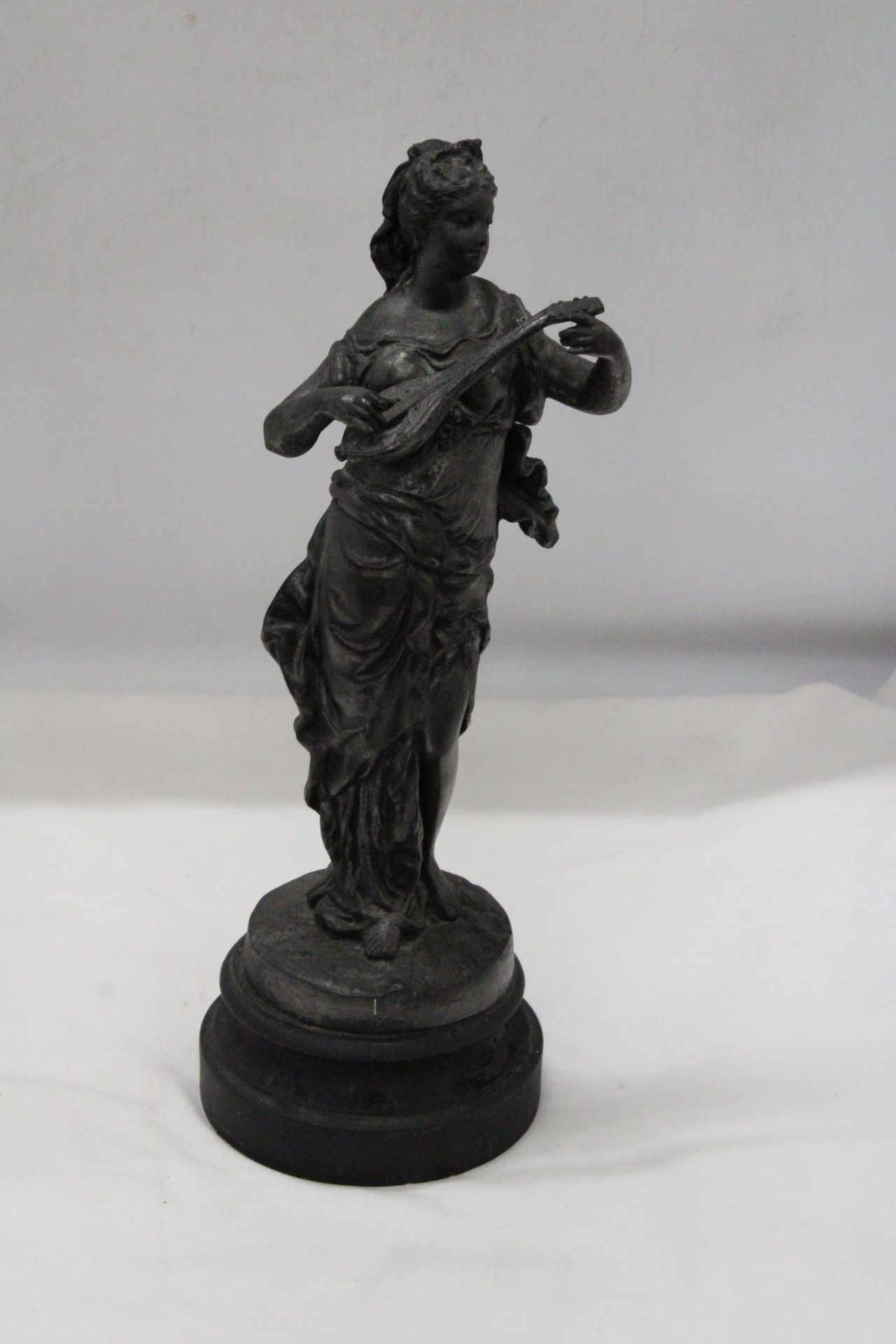 A METAL FIGURE OF A WOMAN ON PLITH