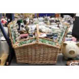 A WICKER PICNIC BASKET WITH LEAF PATTERN INTERIOR TO INCLUDE KNIVES, FORKS, SPOONS, PLATES, SALT AND