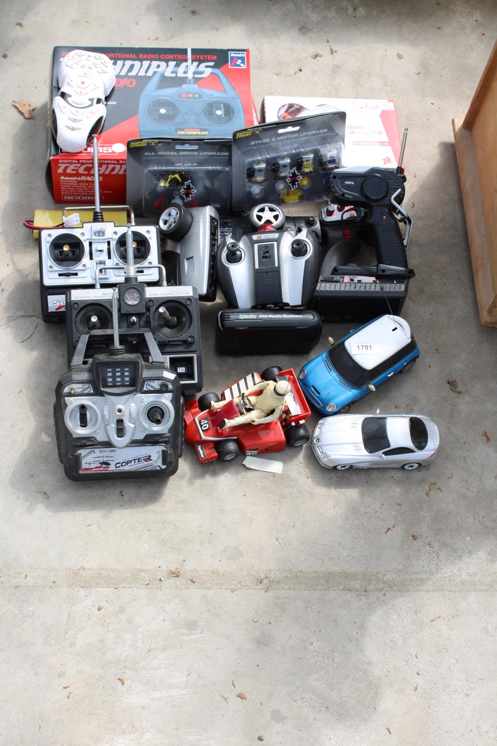 AN ASSORTMENT OF REMOTE CONTROL CARS AND AN ASSORTMENT OF R/C CONTROLLERS