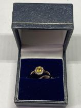 A 9 CARAT GOLD RING WITH CENTRECITRINE SURROUNDED BY CLEAR STONES SIZE K/L IN A PRESENTATION BOX