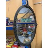 A LARGE OVAL ARTS AND CRAFTS MIRROR