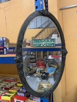 A LARGE OVAL ARTS AND CRAFTS MIRROR