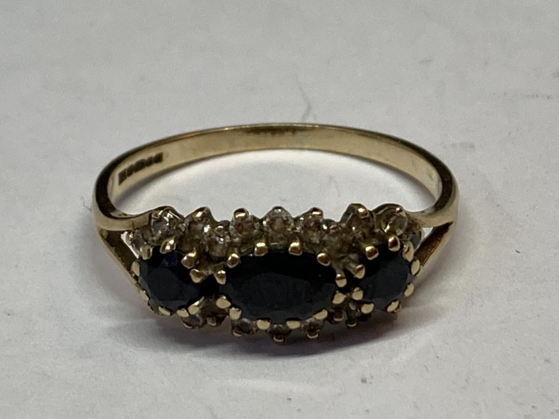 A 9 CARAT GOLD RING WITH THREE SAPPHIRES SURROUNDED BY CUBIC ZIRCONIAS SIZE Q