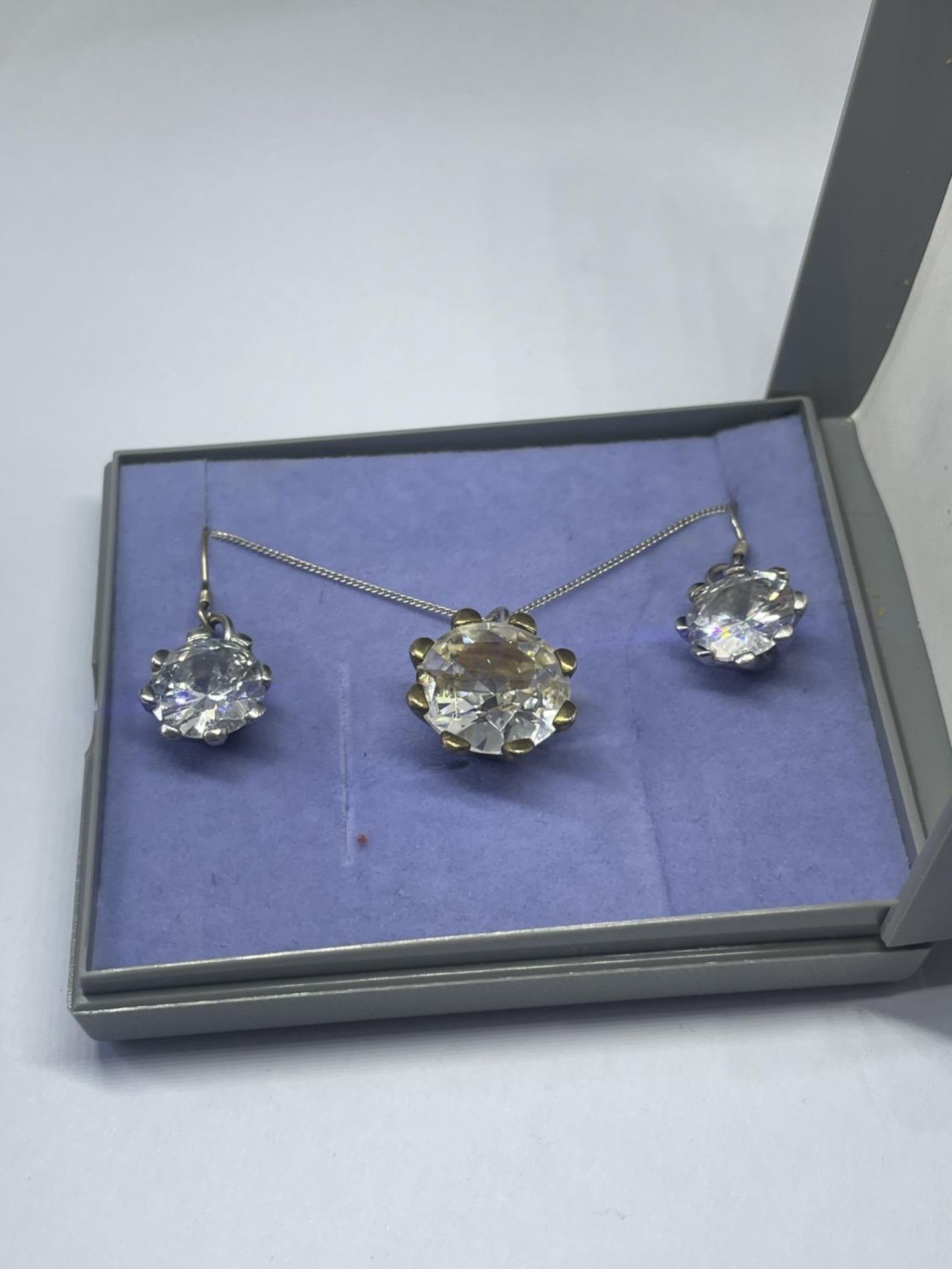 A SILVER CLEAR STONE NECKLACE AND EARRINGS IN A PRESENTATION BOX