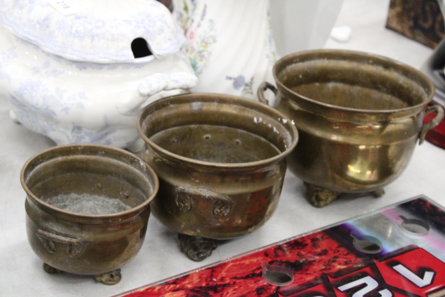 THREE GRADUATED BRASS FOOTED AND HANDLED POTS - Image 2 of 5