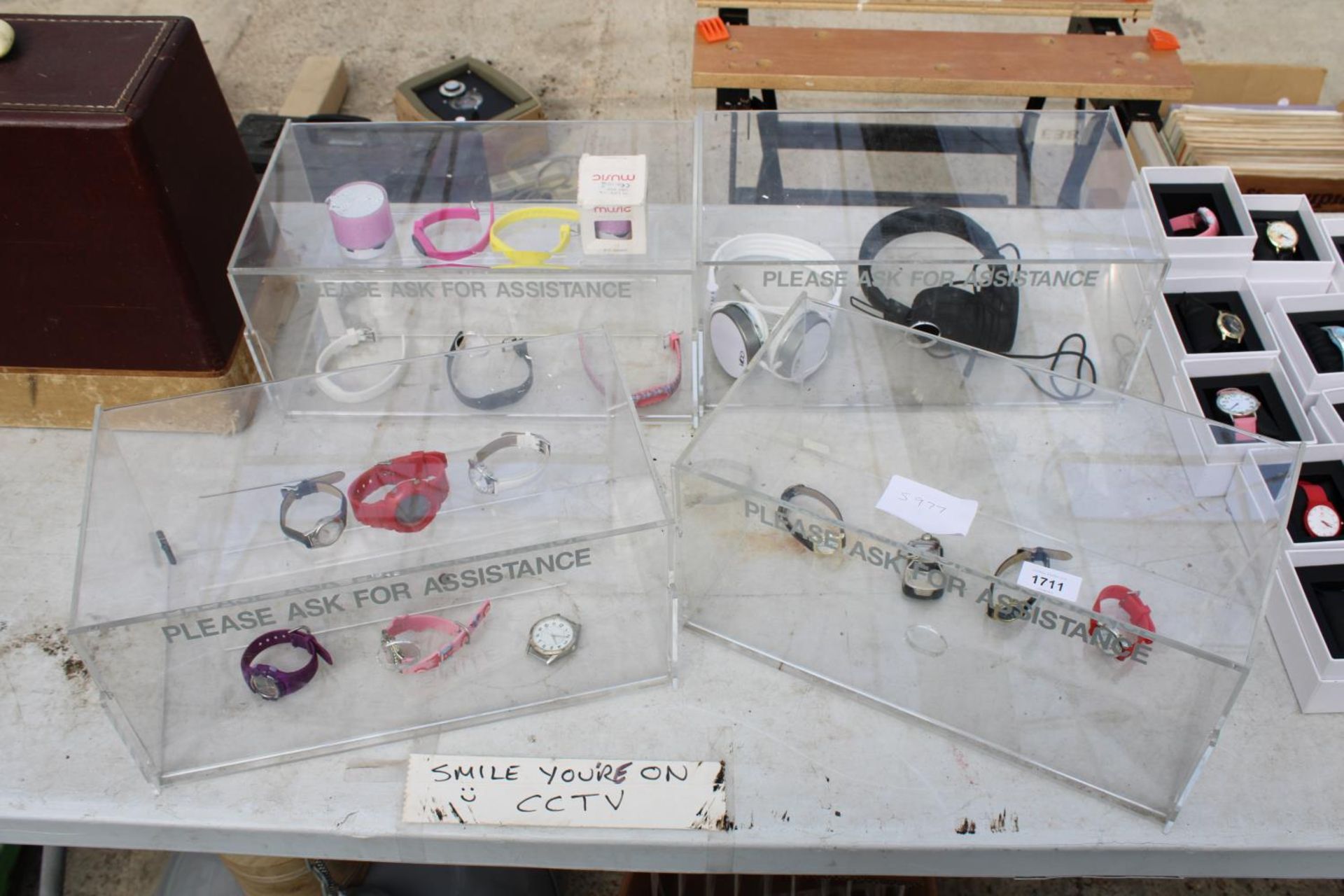 FOUR PLASTIC DISPLAY STANDS WITH AN ASSORTMENT OF FASHION WATCHES AND HEADPHONES