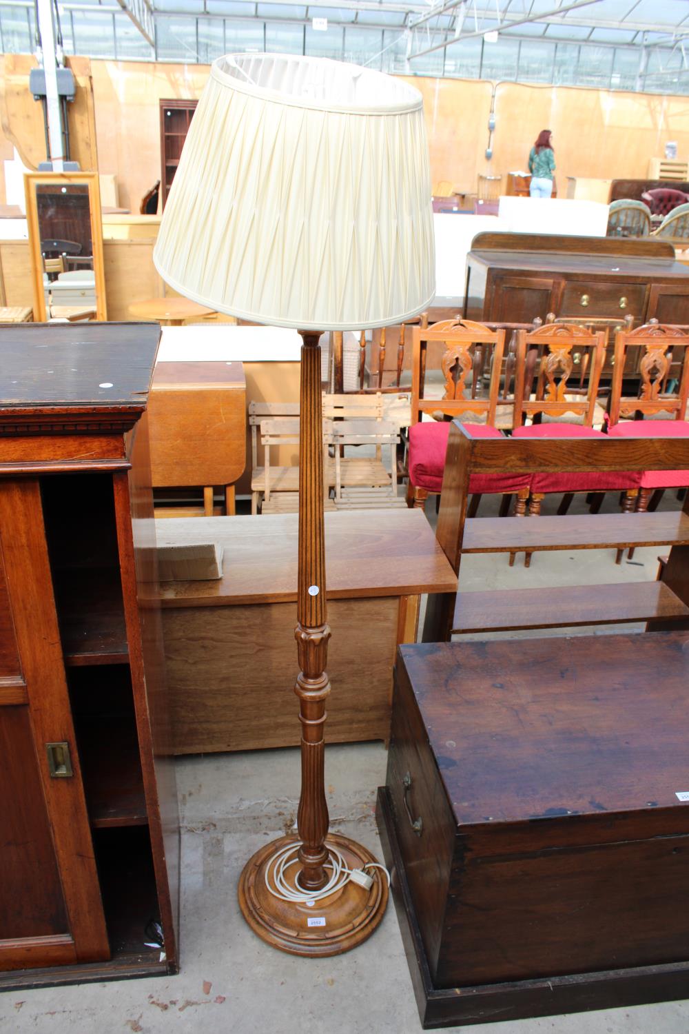 AN OAK STANDARD LAMP WITH TURNED AND FLUTED COLUMN ON ROUND BASE WITH SHADE