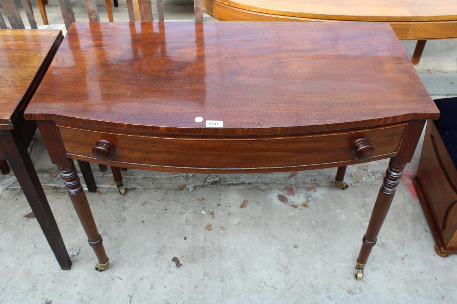 A 19TH CENTURY MAHOGANY BOW-FRONTED SIDE-TABLE WITH SINGLE DRAWER ON TURNED LEGS, 39.5" WIDE