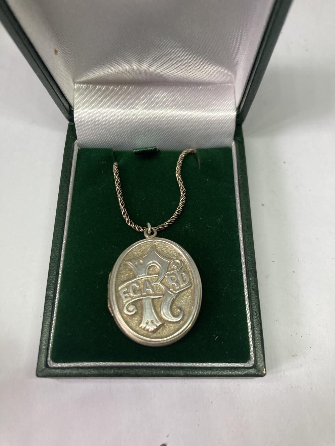 A SILVER NECKLACE AND LOCKET IN A PRESENTATION BOX
