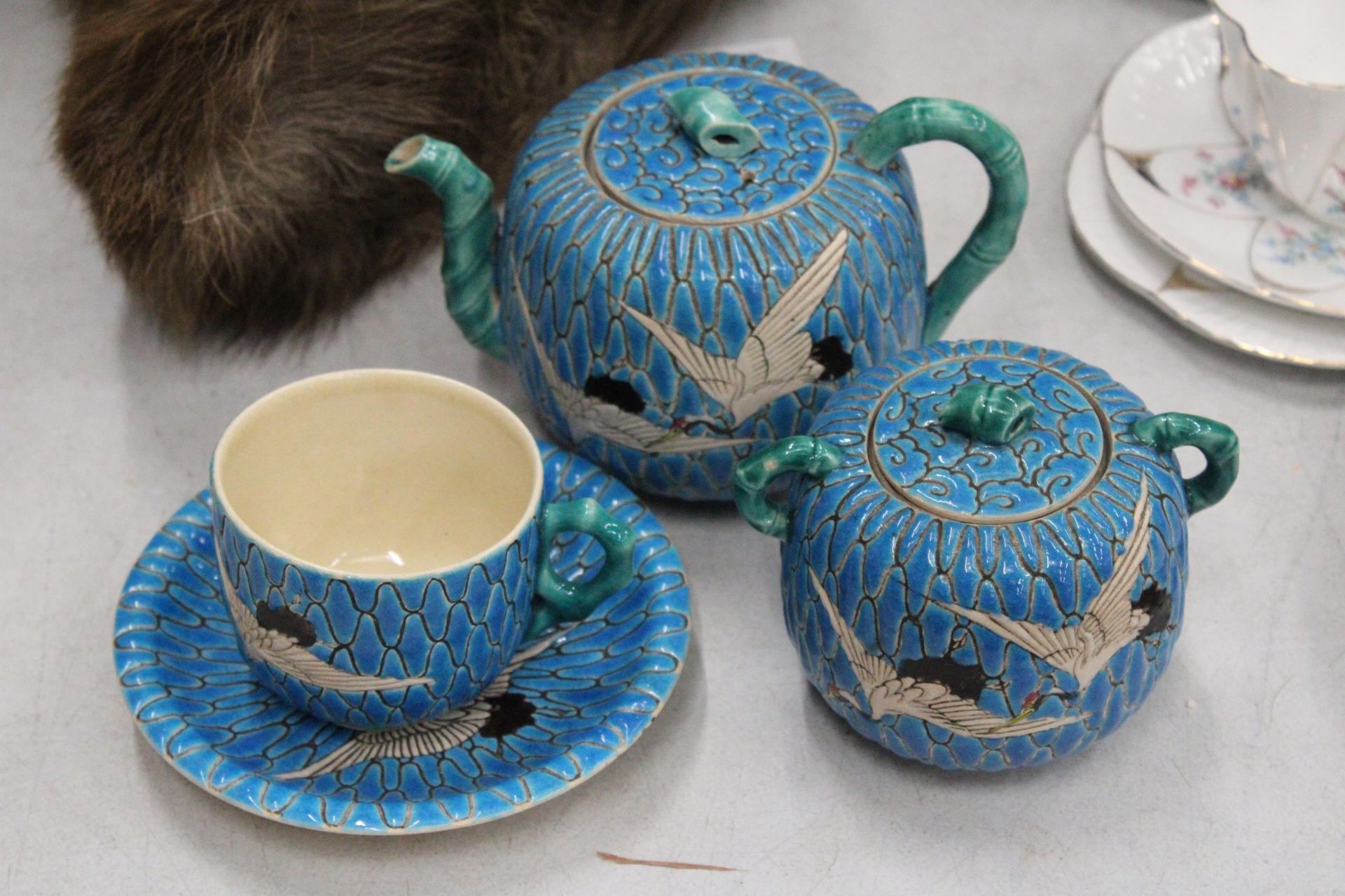 A JAPANESE SATSUMA BLUE MORRIAGE CRANE TEAPOT, LIDDED SUGAR BOWL AND TEACUP AND SAUCER