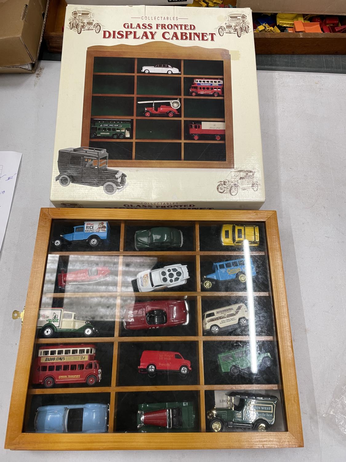 A WOODEN GLASS FRONTED DISPLAY CABINET INCLUDING FIFTEEN MODEL VEHICLES