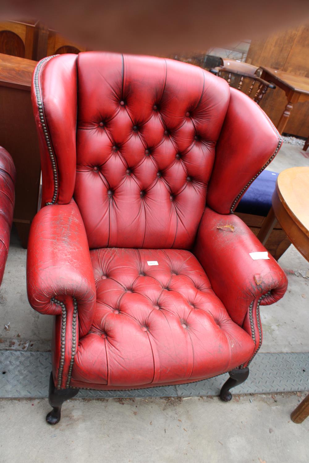 A RED LEATHER BUTTON-BACK WINGED FIRESIDE CHAIR ON FRONT CABRIOLE LEGS