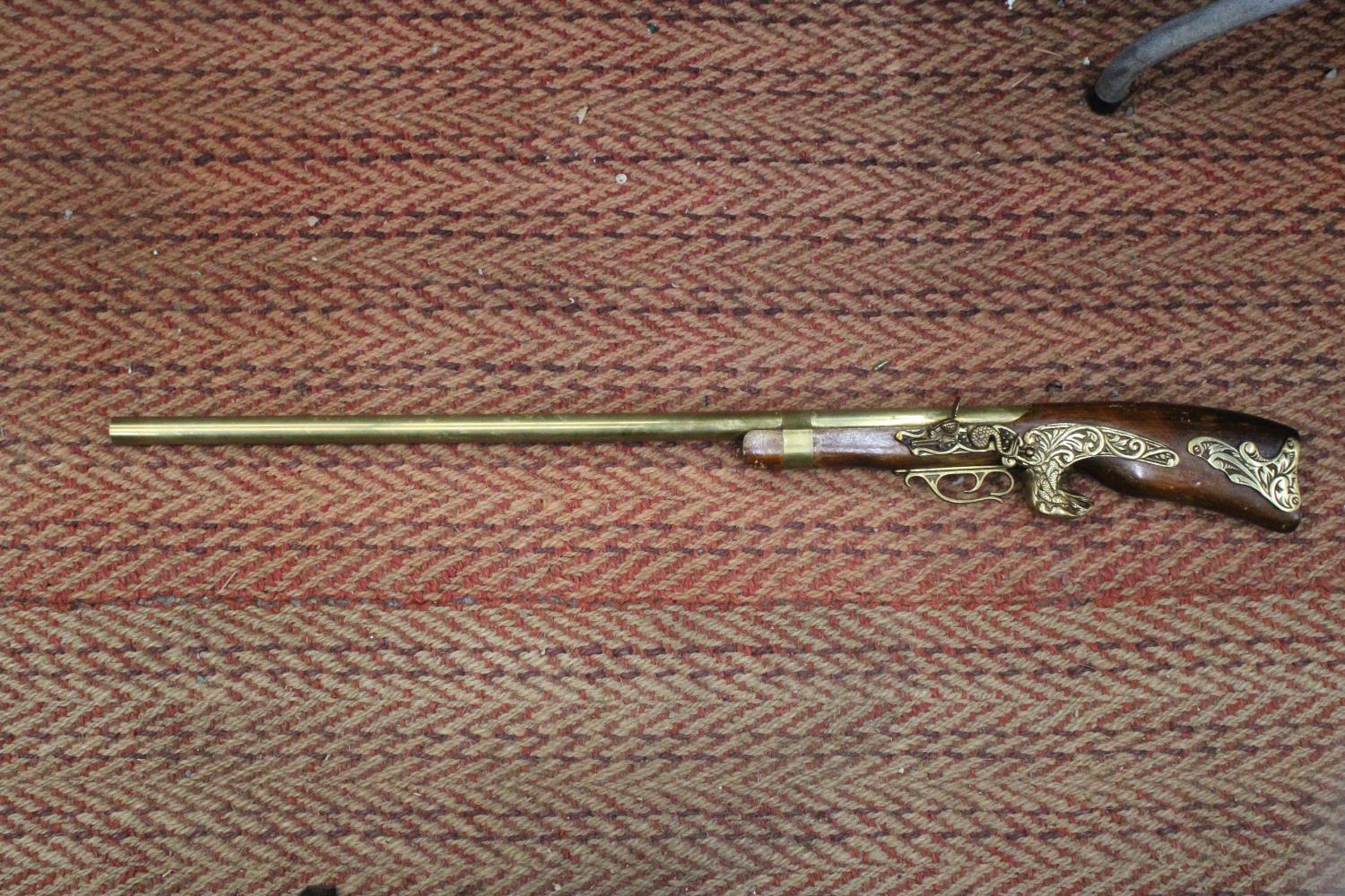 A HEAVY HARDWOOD AND BRASS WALL MOUNTED RIFLE -APPROXIMATELY 104CM