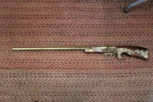 A HEAVY HARDWOOD AND BRASS WALL MOUNTED RIFLE -APPROXIMATELY 104CM