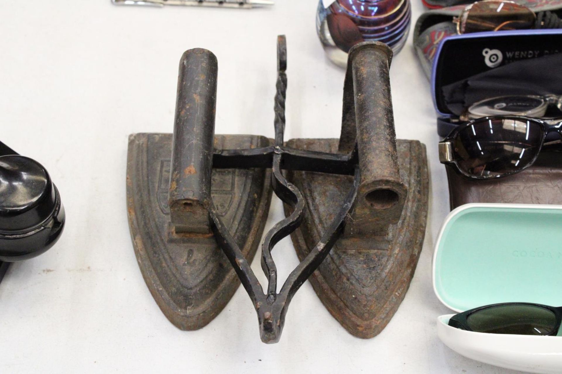 TWO VICTORIAN FLAT IRONS AND AN IRON TRIVET