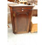 A GEORGE III MAHOGANY CORNER CUPBOARD WITH SHAPED INTERIOR SHELVES AND BRASS HINGES