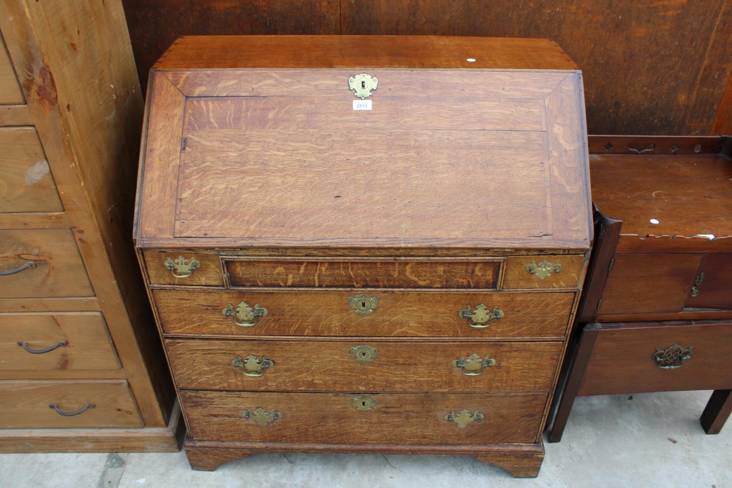 A GEORGE III OAK BUREAU WITH FITTED INTERIOR, TWO SHORT AND THREE LONG GRADUATED DRAWERS TO THE BASE