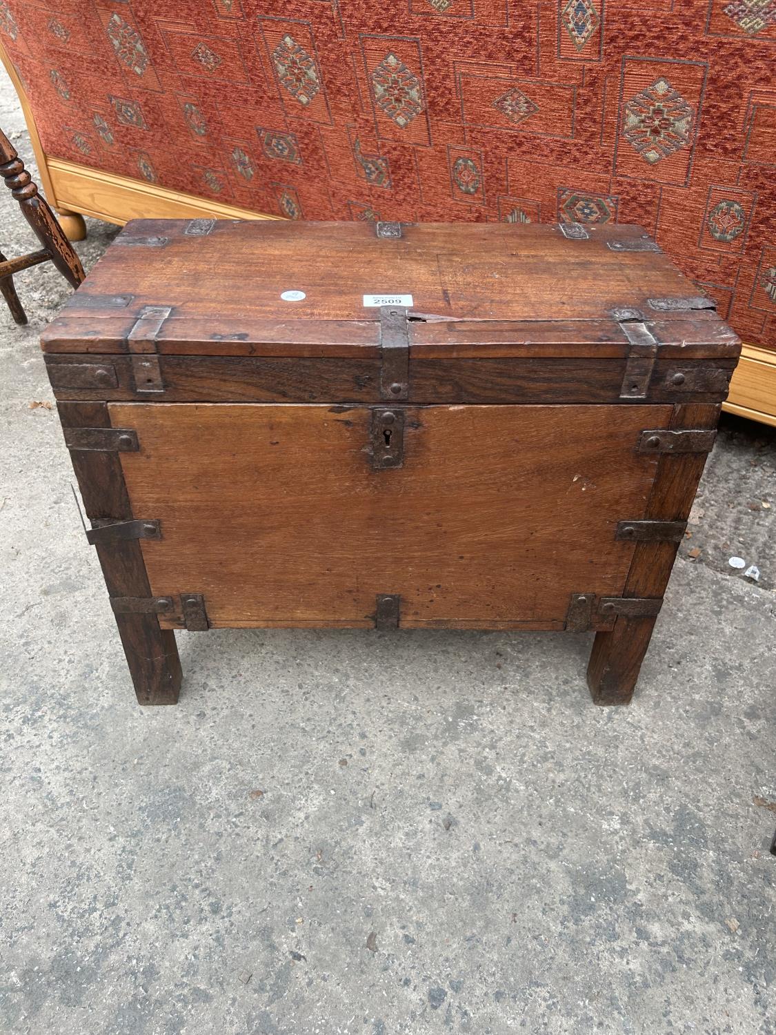 A SMALL HARD WOOD METAL BOUND TRUNK ON LEGS
