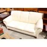 A MODERN CREAM FAUX LEATHER THREE SEATER SETTEE