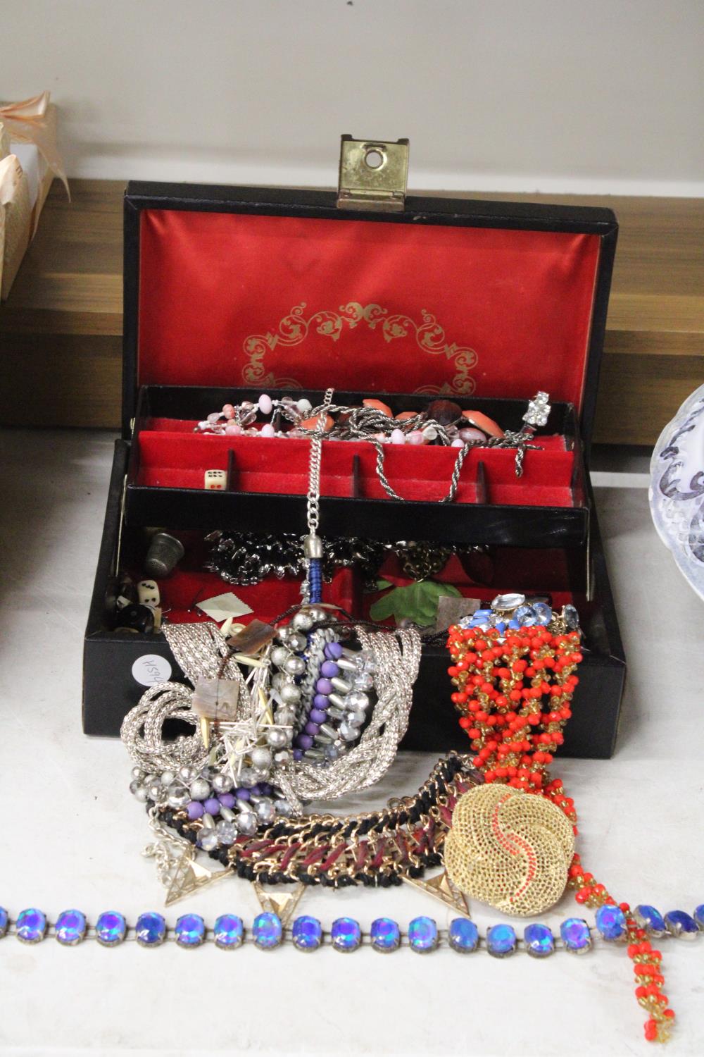 A QUANTITY OF COSTUME JEWELLERY TO INCLUDE NECKLACES, ETC IN A BLACK JEWELLERY BOX WITH RED LINING