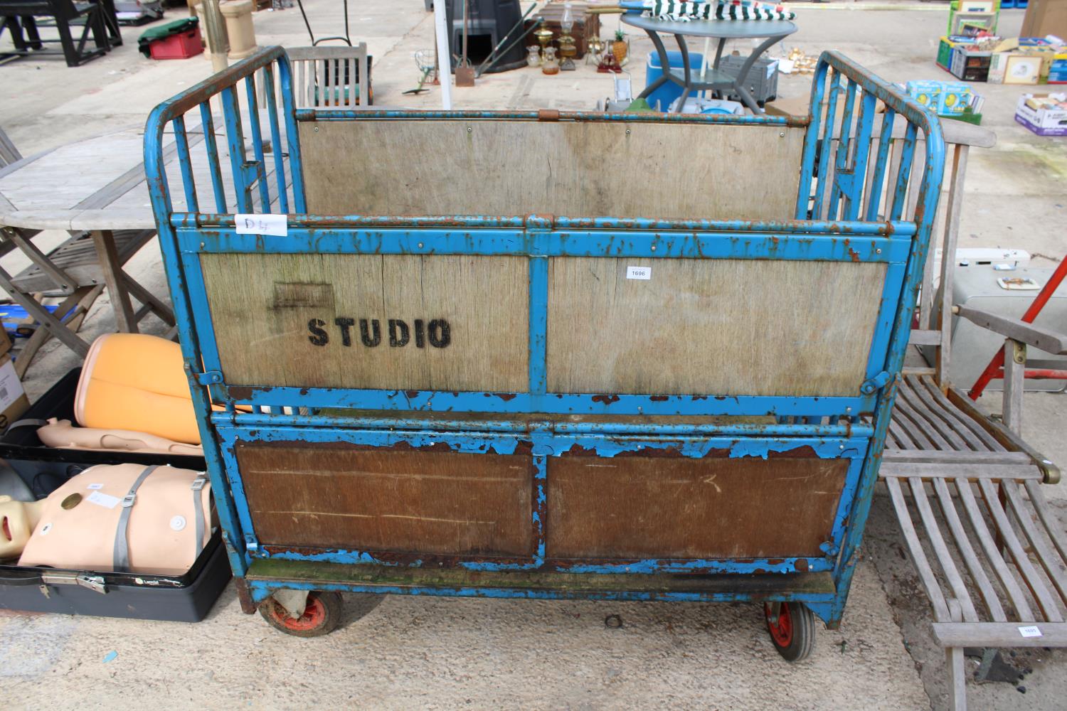 A FOUR WHEELED METAL TROLLEY WITH FOLDING SIDES TO CREATE SHELVES