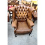 A BROWN CHESTERFIELD STYLE WINGED FIRESIDE CHAIR ON FRONT CABRIOLE LEGS