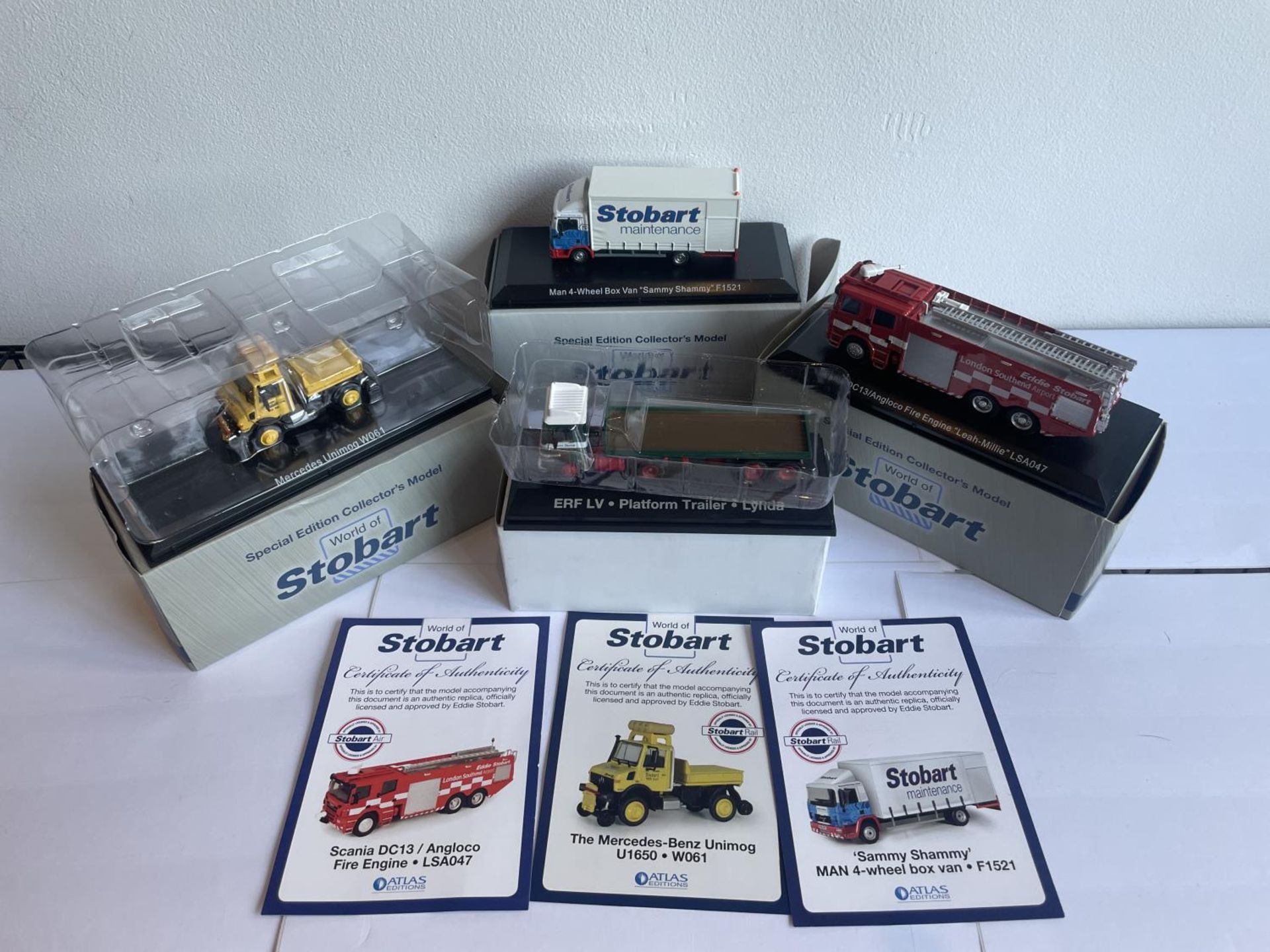 FOUR BOXED STOBART VEHICLES TO INCLUDE A UNIMOG, FIRE ENGINE AND TWO WAGONS THREE WITH COA