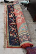 A DECORATIVE RED PATTERNED FRINGED RUG
