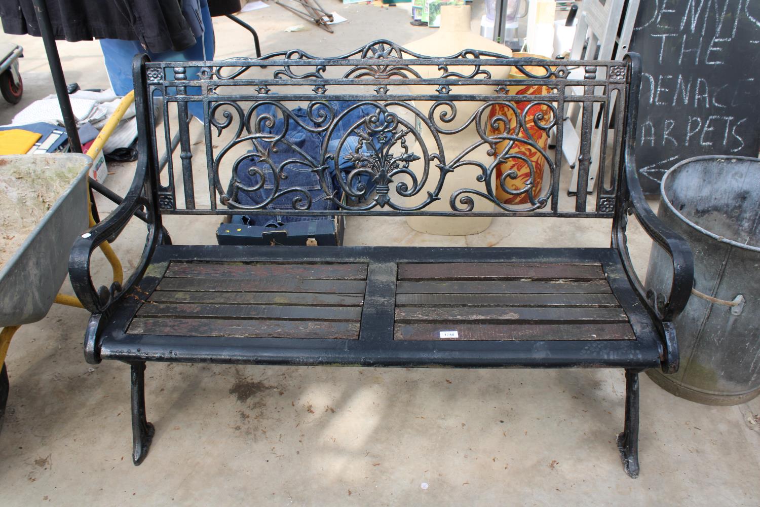 A DECORATIVE WOODEN SLATTED GARDEN BENCH WITH DECORATIVE CAST ENDS AND BACK