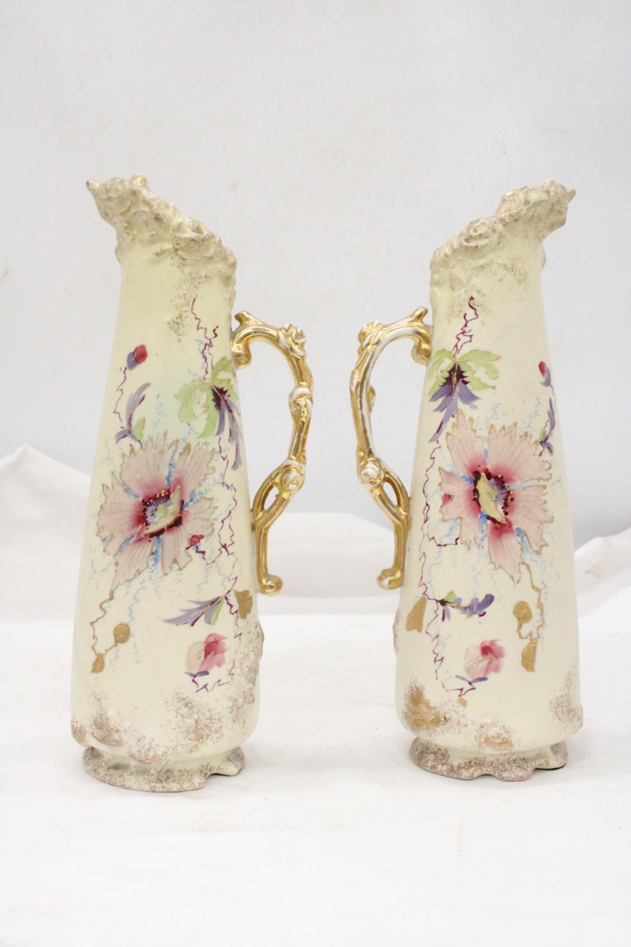 A PAIR OF VICTORIAN JUGS IN IVORY WITH FLORAL AND GILT DECORATION - APPROXIMATELY 31CM HIGH