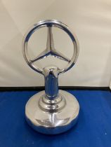 A CHROME MERCEDES SIGN ON A BASE