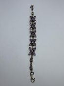 A MARKED SILVER BRACELET WITH PURPLE STONES IN A FLOWER DESIGN