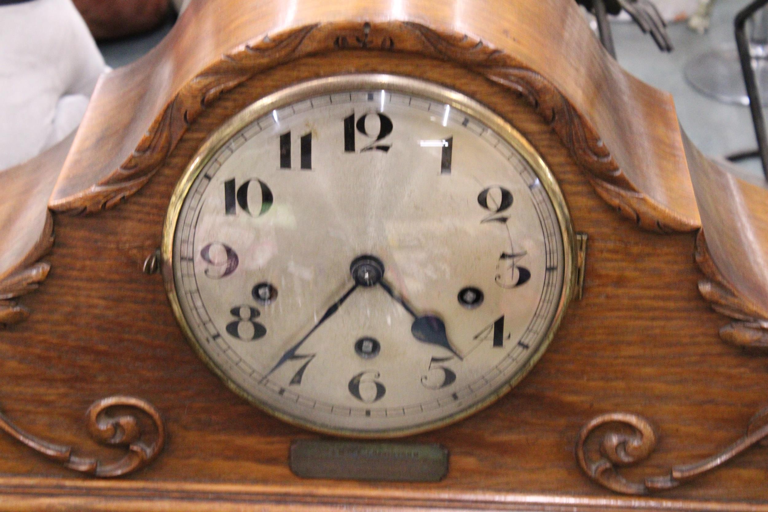 A LARGE OAK CASED MANTLE CLOCK WITH CARVING TO THE FRONT, PENDULUM AND KEY - HAS AN INSCRIPTION - Image 2 of 7