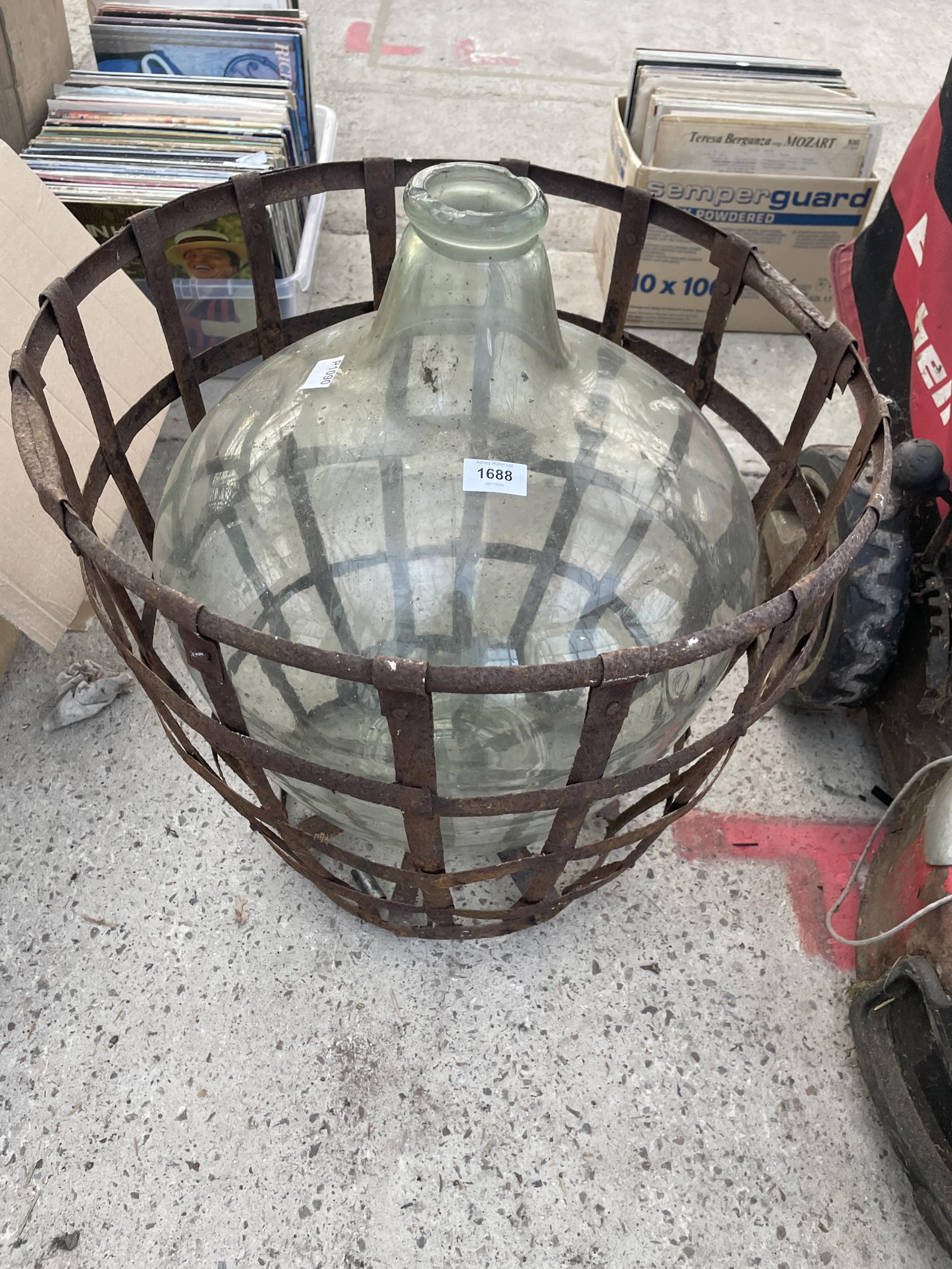 A LARGE VINTAGE GLASS CARBOUY WITH WIRE CAGE