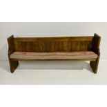 An antique pitch pine church pew with carved detailing.