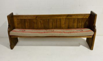 An antique pitch pine church pew with carved detailing.