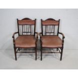 A pair of upholstered oak carver chairs, with carved detailing, raised on tapering legs